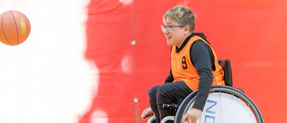 Boy in wheelchair prepares to catch basketball